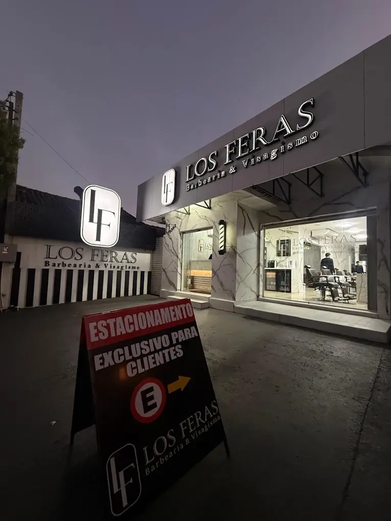 Fachada da Barbearia Los Feras ao anoitecer, com o letreiro iluminado