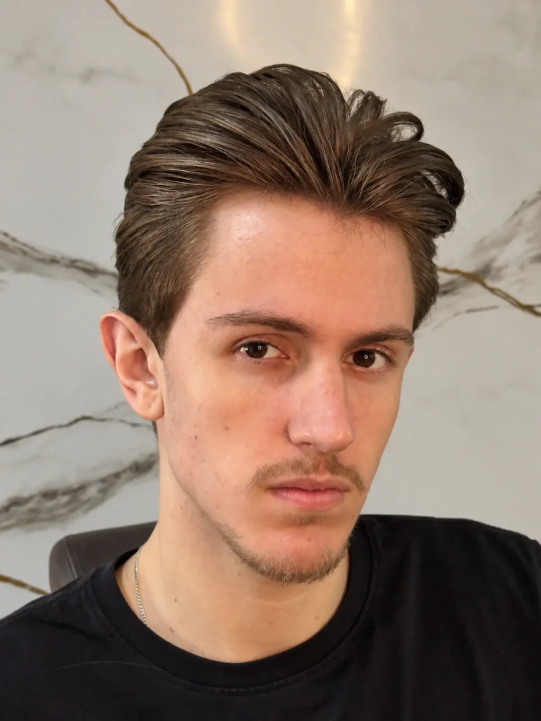 Cliente de frente com o corte finalizado, cabelo penteado para o lado, no salão da Los Feras
