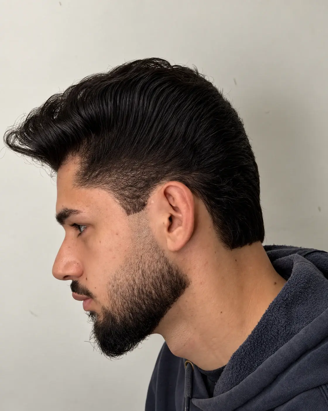 Cliente de perfil com corte e barba finalizados no mesmo atendimento